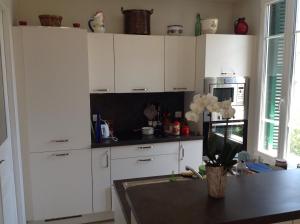 een keuken met witte kasten en een tafel bij Appartement Tout Confort avec Terrasse in Nice