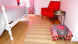 a bedroom with a bed and a red chair and a rug at Casinhas da Ajuda nº 29 in Lisbon