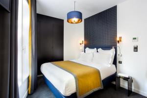 sypialnia z dużym łóżkiem z niebieskim zagłówkiem w obiekcie Hôtel Clarisse w Paryżu
