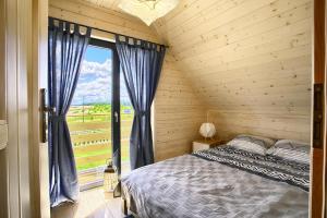 a bedroom with a bed and a large window at Domki Modrzewiowa 20 in Rewal