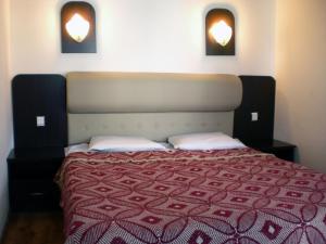 um quarto com uma cama com um cobertor vermelho e duas luzes em Гостоприемница Георги em Kalofer