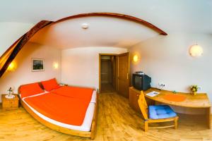 Schlafzimmer mit einem orangenen Bett und einem Schreibtisch in der Unterkunft Frühstückspension Zanglhof in Lannach