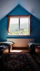 Habitación con ventana grande y pared azul. en Green Hostel, en Gorists'ikhe