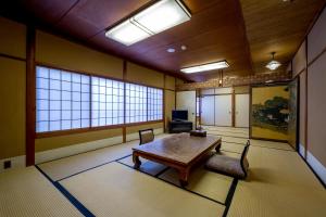a room with a wooden table and chairs and windows at Kyoto Ryokan SAKANOUE in Kyoto