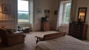 a bedroom with a bed and a chair and a dresser at Kelly House Country B&B in Lifton