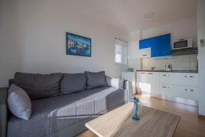 a living room with a gray couch and a kitchen at Katarina apartmani in Podstrana