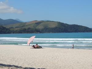 a person laying on the beach with a surfboard at Pousada Mosaico Brasil - Maresias in Maresias