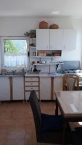 cocina con armarios blancos y mesa de madera en Rooms Sijak en Bar