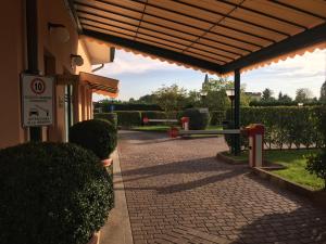 a building with a brick walkway with a bench and bushes at Hotel Motel Luna in Segrate