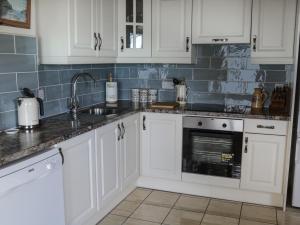 una cocina con armarios blancos y fregadero en Killary Bay View House en Renvyle