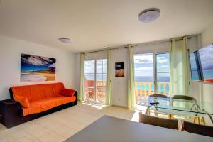 sala de estar con sofá naranja y mesa de cristal en Your Ocean Suite, en Costa Calma