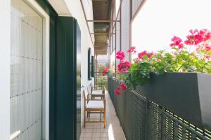 einen Balkon mit Stühlen und Blumen auf einem Gebäude in der Unterkunft Casa Allori in Belluno
