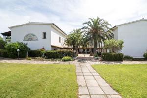 a white house with palm trees and a lawn at White Sand Residence in Murta Maria