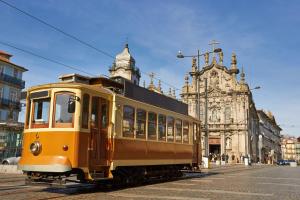 a yellow trolley car on a street in a city at Host Wise - Cozy Quiet Flat - Trindade Station in Porto