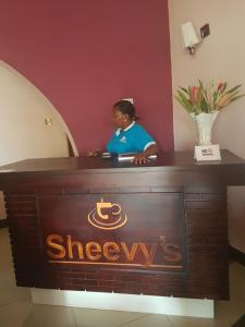una mujer sentada en un escritorio en una habitación en Sheevy"s Bed N Breakfast, en Fort Portal
