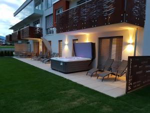 patio z wanną z hydromasażem i krzesłami obok budynku w obiekcie SPA-Lounge w mieście Seeboden
