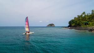 a small sail boat in the water near a island at Club Santana Beach & Resort in SantʼAna