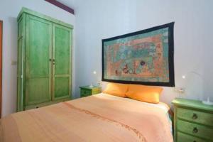 グラナダにあるSpacious, sunny and quiet Albayzin apartmentの緑のキャビネットとオレンジの枕付きのベッドが備わるベッドルーム1室が備わります。