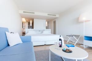a bedroom with a bed and a table and a couch at Palmares Beach House Hotel - Adults Only in Lagos
