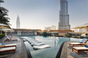 a row of lounge chairs in front of a large pool of water at Address Boulevard in Dubai