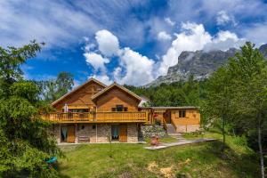a log cabin with a deck and mountains in the background at Gite&Spa le Montagnard in Saint-Jean-Saint-Nicolas