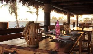 a wooden table with plates and a bottle on the beach at Souly Ecolodge Salalah in Salalah