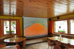 TV de pantalla grande en una habitación con pista de tenis. en Berggasthaus Gemsli en Sankt Antönien