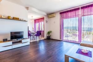 a living room with a television and a dining room with a table at Apartman - The view in Krk