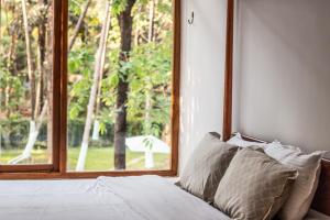 a bedroom with a window and a bed with pillows at Botanique Goa in Assagao