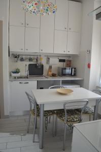 モンテロッソ・アル・マーレにあるLa Murariaの白いキャビネット、テーブルと椅子付きのキッチンが備わります。