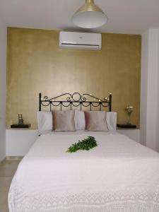 マラガにあるApartamento La Victoriaの白いベッド1台(植物付)が備わるベッドルームです。