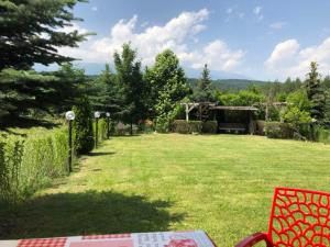 a yard with a red chair in the grass at Katarino Villa Nature Escape in Razlog