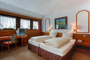 two beds in a room with a desk and a tv at Hotel Stern by EMPA in Ulm