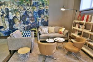 a living room with a couch and chairs and a painting at Mercure Périgueux Centre Historique in Périgueux