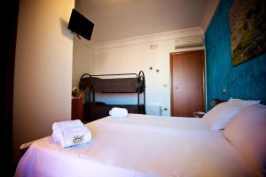 1 dormitorio con 1 cama blanca grande y toallas. en B&B NiloSira, en Morciano di Leuca