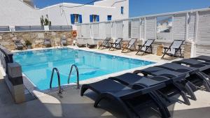 a large swimming pool with blue chairs and tables at Markos Village Pension in Ios Chora