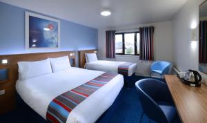 a hotel room with two beds and a desk at Travelodge Waterford in Waterford