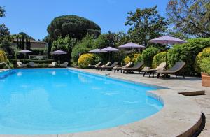 a swimming pool with lounge chairs and umbrellas at Mas De Chastelas in Saint-Tropez
