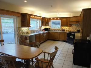 uma cozinha com uma mesa de madeira, uma mesa e cadeiras em Applewood Heights em Glenariff