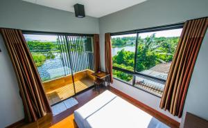 um quarto com duas grandes janelas com vista para um rio em Na Siri Lake View em Samut Prakan