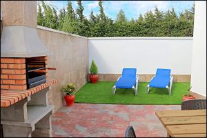 a patio with two blue chairs and a fireplace at Bungalow La Roa V in Conil de la Frontera