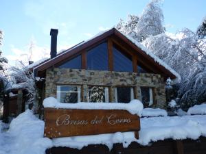 a sign in front of a cabin in the snow at Hostería Brisas del Cerro in Villa La Angostura