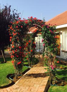 un arco con flores rojas en una pasarela de ladrillo en Welcome Guest House, en Vereeniging