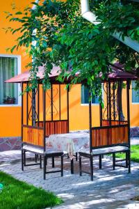 a group of benches sitting under a gazebo at Osobyi Guest house in Cholpon-Ata