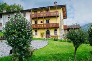 a yellow building with a balcony on top of a yard at Agriturismo il posto delle fragole in San Giovanni Bianco