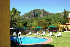 una piscina con sillas y sombrillas frente a una montaña en Las Casitas Tepoztlán en Tepoztlán