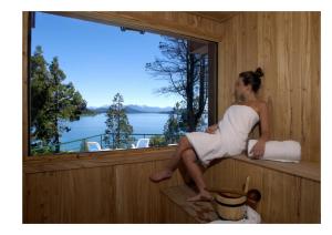 a woman sitting on a wooden bench in front of a window at Charming Luxury Lodge & Private Spa in San Carlos de Bariloche