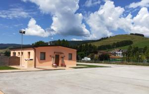 a small pink building with a hill in the background at B&B 3409ft Aeroporto in Asiago