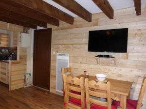 Zimmer mit einer Holzwand, einem Tisch und einem TV in der Unterkunft CAP DES NEIGES 1 in Barcelonnette