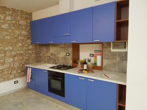 a kitchen with blue cabinets and a stone wall at la maison de rêve in Camaiore